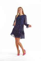 Beautiful young blonde woman in dark blue dress with floral print isolated on white background