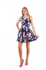 Beautiful young blonde woman in dark blue dress with floral print isolated on white background