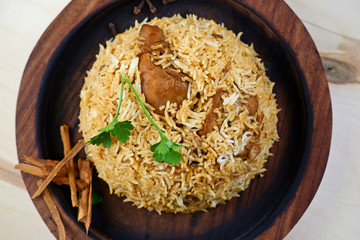 Indian traditional dish with rice and coriander leaf on wooden tray. Cinnamon bark on the side. Top view.