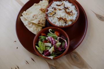 Tradition indian bread with rice and vegetable salat on ceramic plate.