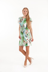 Beautiful young blonde woman in white dress with tropical print isolated on white background