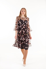 Beautiful young blonde woman in black dress with floral embroidery isolated on white background