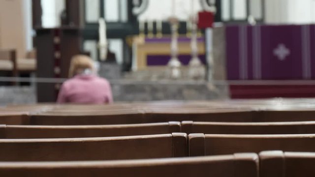 Lonely woman praying in a Catholic Christian church with benches in Belgium   