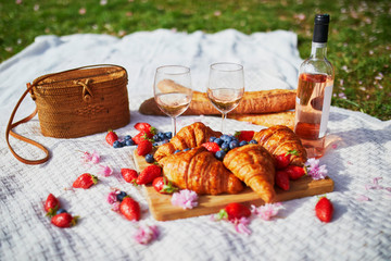 Fototapeta na wymiar Beautiful picnic with rose wine, French croissants and fresh berries