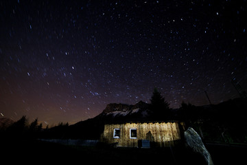 long time exposure with polaris and colorful star trails in the austrian alps with a cabin
