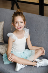 positive little girl sitting on the sofa at home