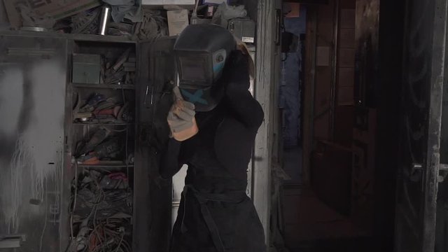 Girl welds steel parts in the workshop