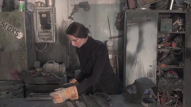 Girl welds steel parts in the workshop