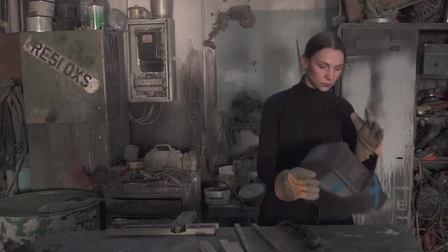 Girl welds steel parts in the workshop