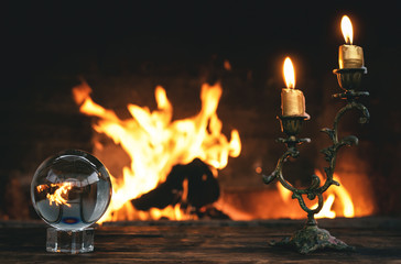 Fototapeta na wymiar Crystal ball on a magic table on a burning fire flame background.