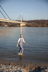 one young man, walking in river barefoot.