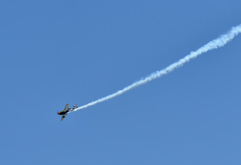 Single one sport plane of aerobatic team vapour trails in blue sky. Plane white vapour trails tracks background. Plane aerobatic maneuver stunt. Budapest, Hungary.