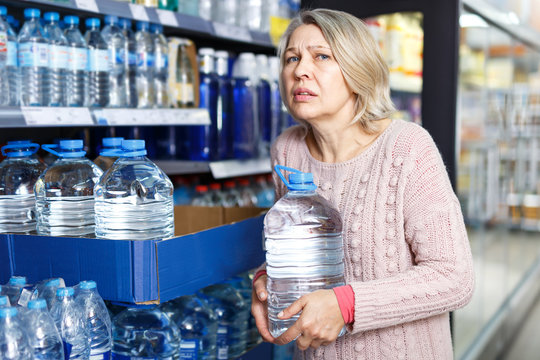 Tense Modern Woman Lifting Heavy Bottle Water