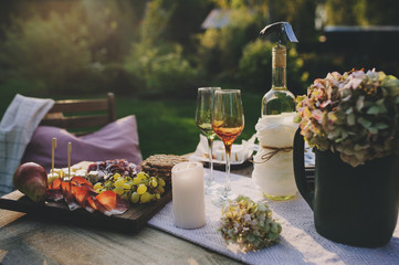 delicious cheese, ham and fruits served on wooden cutting board outdoor on summer garden party