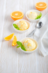 Orange ice cream in a bowls on a white wooden table.