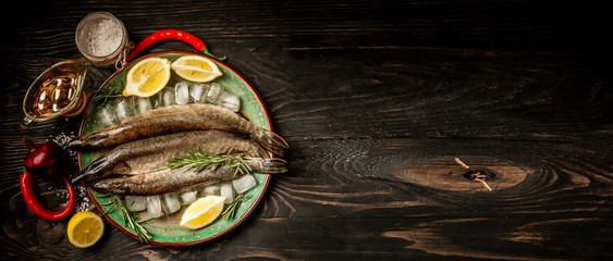Tree raw pike with spices on an old wooden background. Raw fish with spices for cooking. top view, space for text