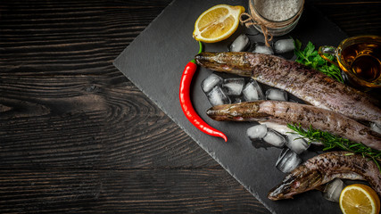 Raw fresh river fish on plate cutting board an old wooden background. fish with spices for cooking. top view, space for text