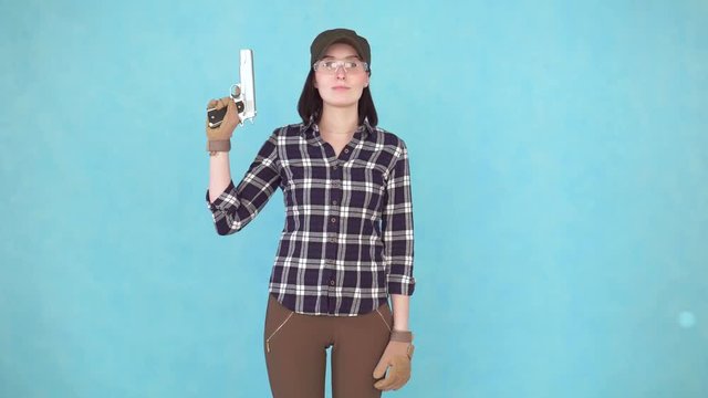 girl shooter with gun and glasses looking at camera smiling