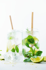 Close up of two glasses with tropical mojito cocktail on light background with copy space. Summer time vacation concept.
