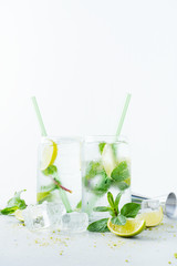 Close up of two glasses with tropical mojito cocktail on light background with copy space. Summer time vacation concept.