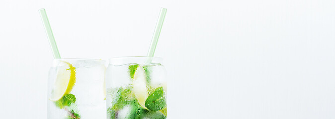 Close up of two glasses with tropical mojito cocktail on light background with copy space. Summer time concept. Long wide banner with copy space.