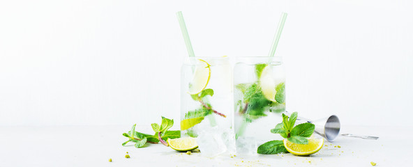 Close up of two glasses with tropical mojito cocktail on light background. Long wide banner with...