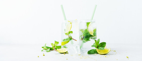Close up of two glasses with tropical mojito cocktail on light background with copy space. Summer time concept. Long wide banner with copy space.