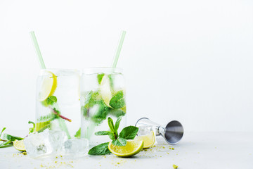 Close up of two glasses with tropical mojito cocktail on light background with copy space. Summer time vacation concept.