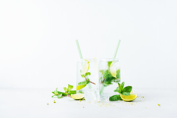 Close up of two glasses with tropical mojito cocktail on light background with copy space. Summer time vacation concept.