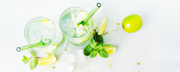 Fototapeta na wymiar Top view of two glasses with tropical mojito cocktail on light serface. Summer time vacation concept.Long wide banner with copy space.