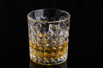 Whiskey with ice in rocks glass on black background