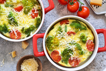 Casserole with broccoli, tomatoes and parmesan on a concrete background. View from above.