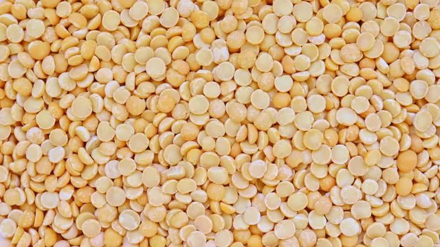 Dry yellow split peas rotation background texture, vegetable protein source fo vegetarians and vegans