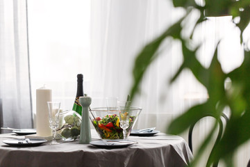 Dining room table with, champagne, candles and salad, set for anniversary dinner
