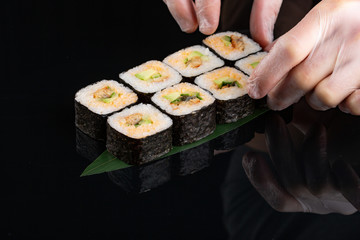 Traditional japanese sushi roll with sea eel, and avocado on a glossy black background