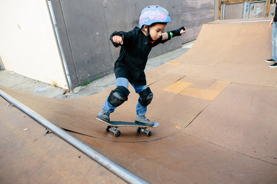 A young boy stays focused and balanced while skating a half pipe