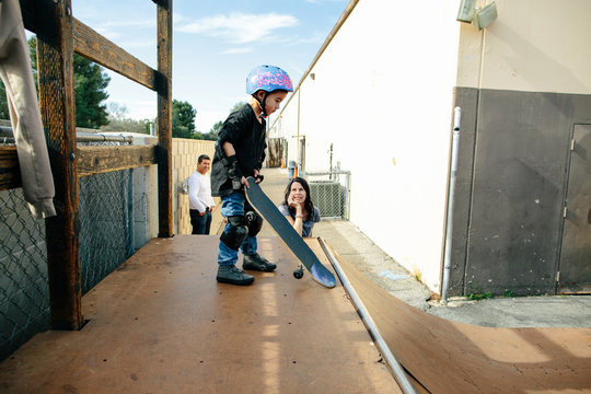 Mother smiles watching son set up to drop in on half pipe