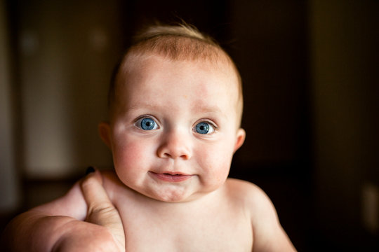 Portrait of shirtless baby boy smiling and looking straight at camera