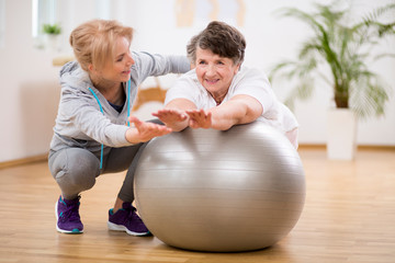 Disabled senior woman exercising on the ball with physiotherapist
