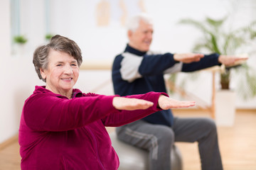 Elderly woman exercising during pilates for seniors in retirement home