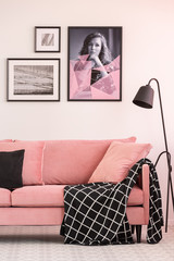 Gallery of posters on white wall in fashionable living room interior with pink couch and industrial...
