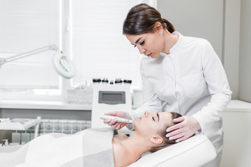 Obraz na płótnie Canvas Woman gets native electro stimulating lifting skin therapy at Spa salon side view