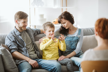 Caring parents and misbehaving boy during therapy session with counselor