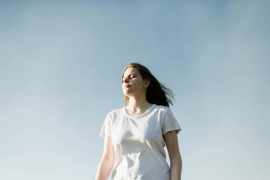 Dreamy portrait of a young brunette woman  at blue sky background with