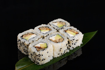 closeup philadelphia roll sushi with eel cucumber, cream cheese and sesame seeds served on black background