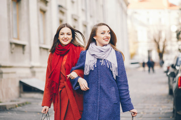 two beautiful and stylish girlfriends walking around the spring city with packages and shopping