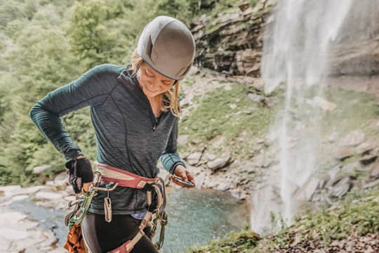Woman puts gear back on harness after rappelling waterfall in Catskill