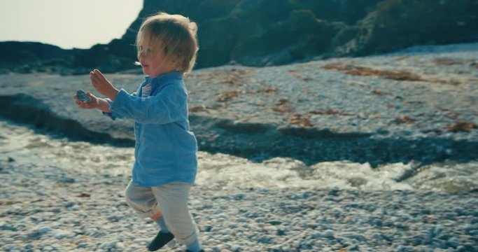Little toddler picking up stones and bringing them to his mother on the beach