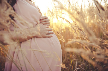 Close up of pregnant belly in nature. Pregnant girl in the sunset, pregnant woman relaxing outside...