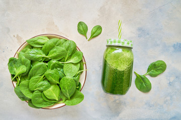 Green smoothie from spinach and kale in glass jar and plate with fresh spinach. Copy space.